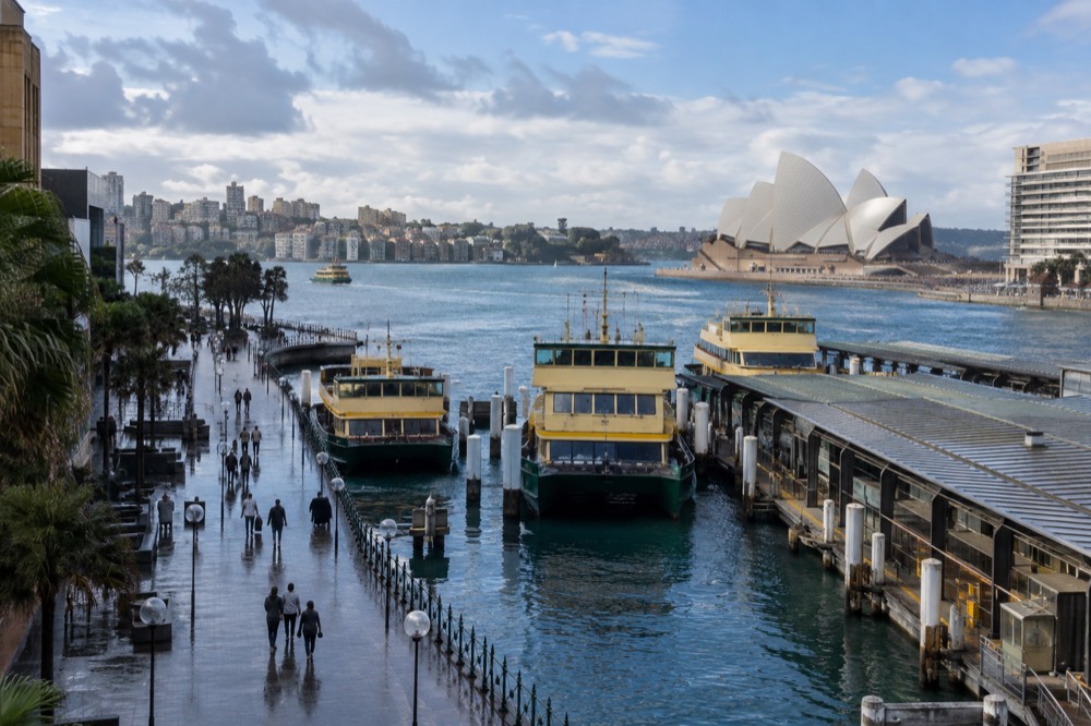The Circular Quay promenade with ferries at the wharves and the Opera House in the distance