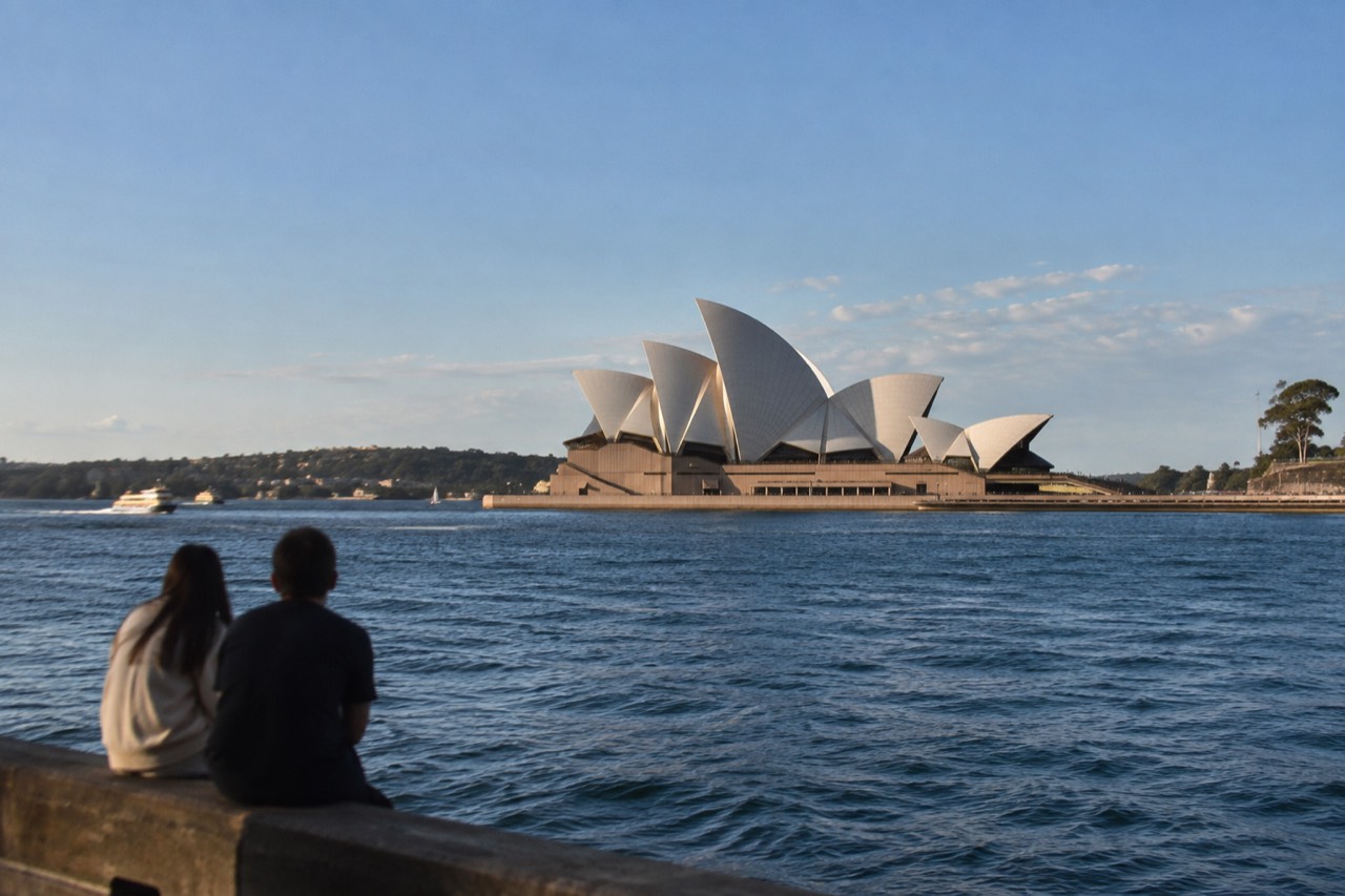 The white sails of the Sydney Opera House against a blue sky above the harbour