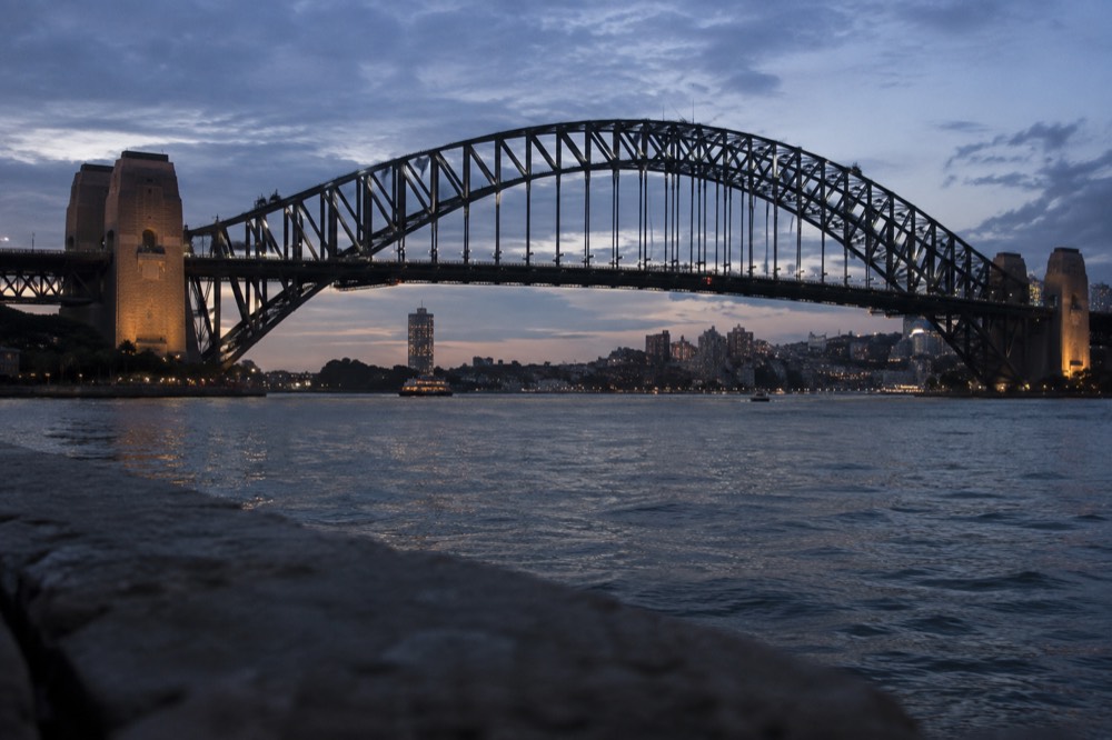 The upper arch of the Sydney Harbour Bridge seen from below, with ladders and walkways along the steelwork