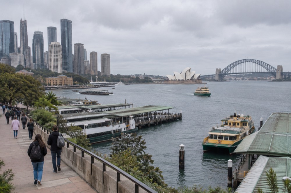 Visitors walking a coastal path above the ocean with the city skyline behind
