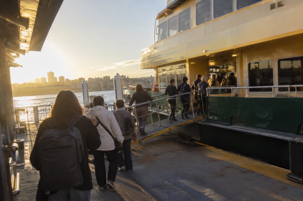 Passengers boarding a green and yellow Sydney ferry at a harbour wharf