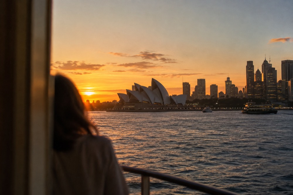 Sydney Harbour at dusk with the Opera House and city skyline lit against the evening sky