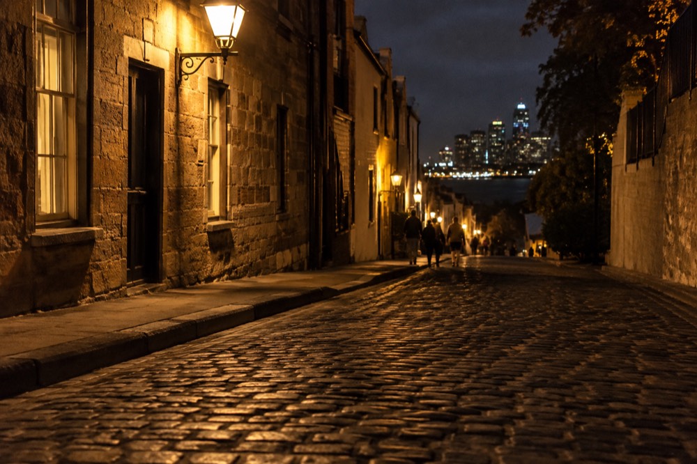 Cobblestone lane in The Rocks at night, lit by warm lamps beside heritage sandstone buildings