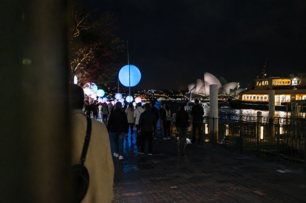 Crowds walking past illuminated light installations along the Circular Quay foreshore at night