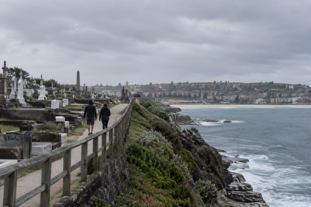 A headland path beside a historic cemetery with the ocean beyond