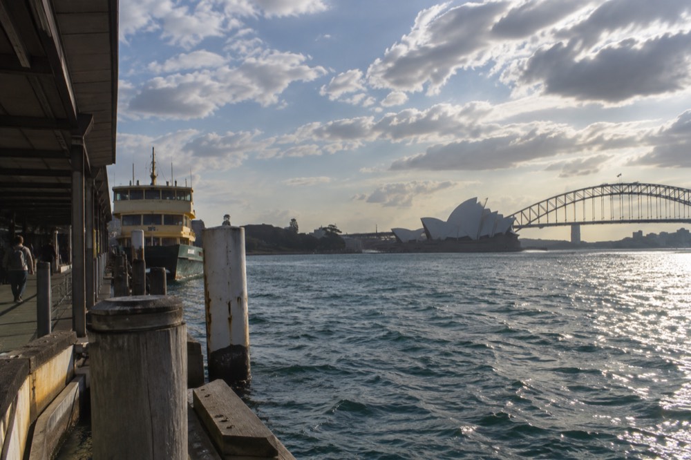 A cliff-top walking path above an ocean beach with headlands receding into haze