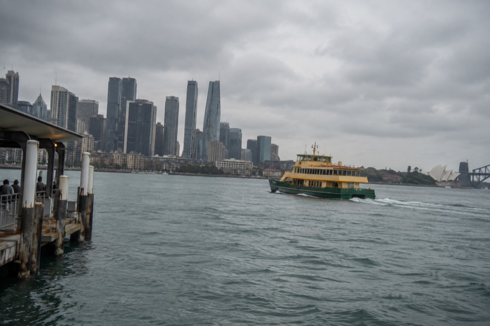 A Sydney ferry crossing the harbour toward Manly with the city skyline behind
