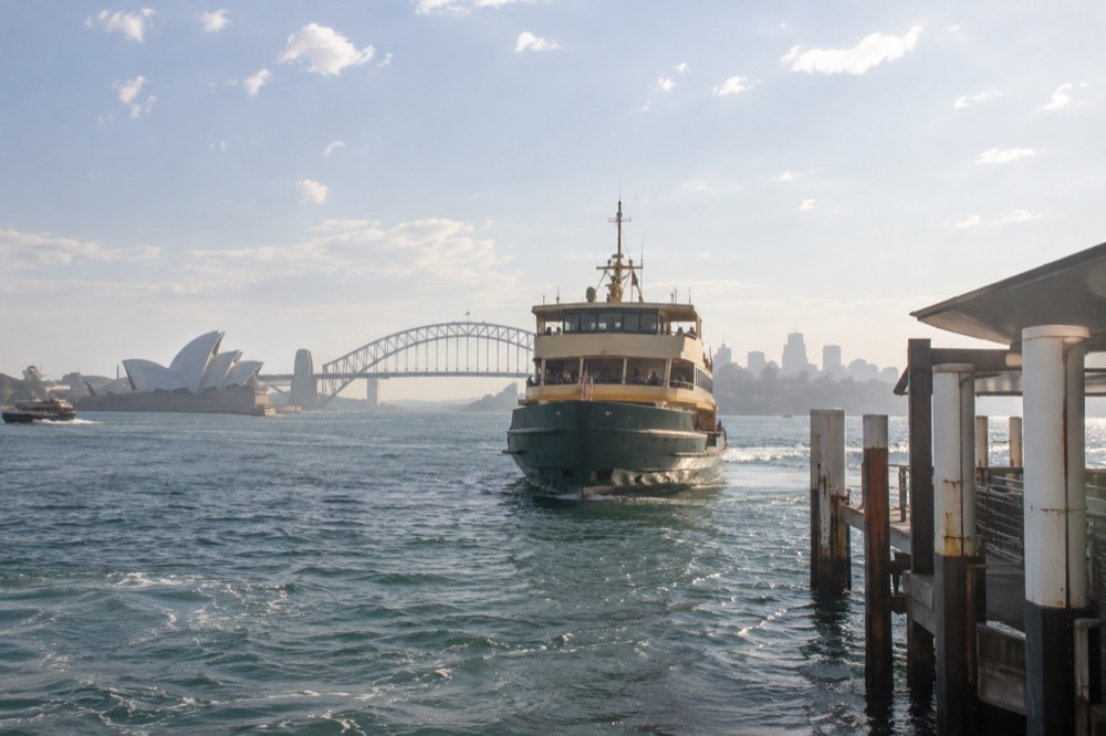 Sydney Harbour ferry approaching a wharf with the city skyline behind it
