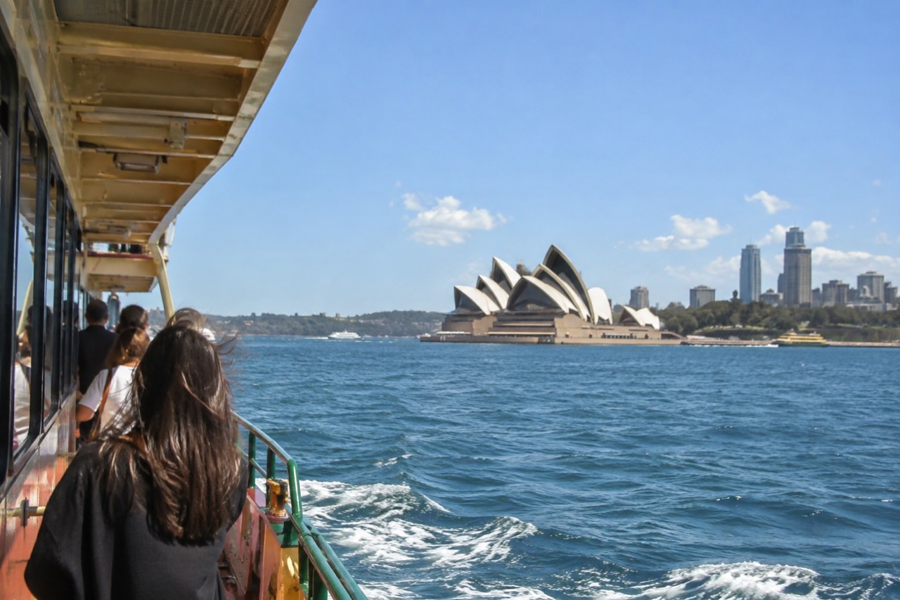 Sydney Opera House sails seen across the water from a harbour ferry at midday