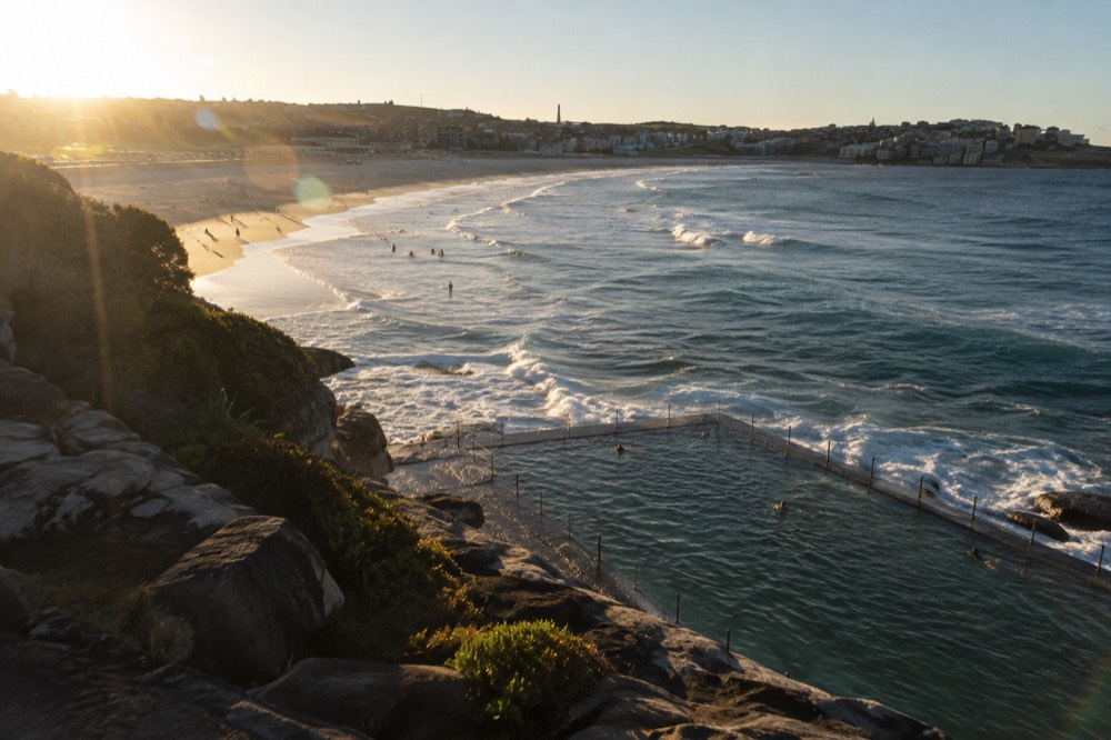 Bondi Beach seen from the sandstone cliffs at the south end, with the ocean pool at the water's edge