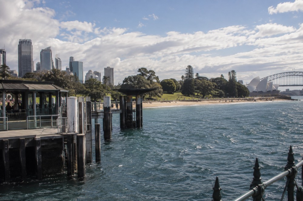 A wide sandy bay with a grassy park behind it and a path along the foreshore
