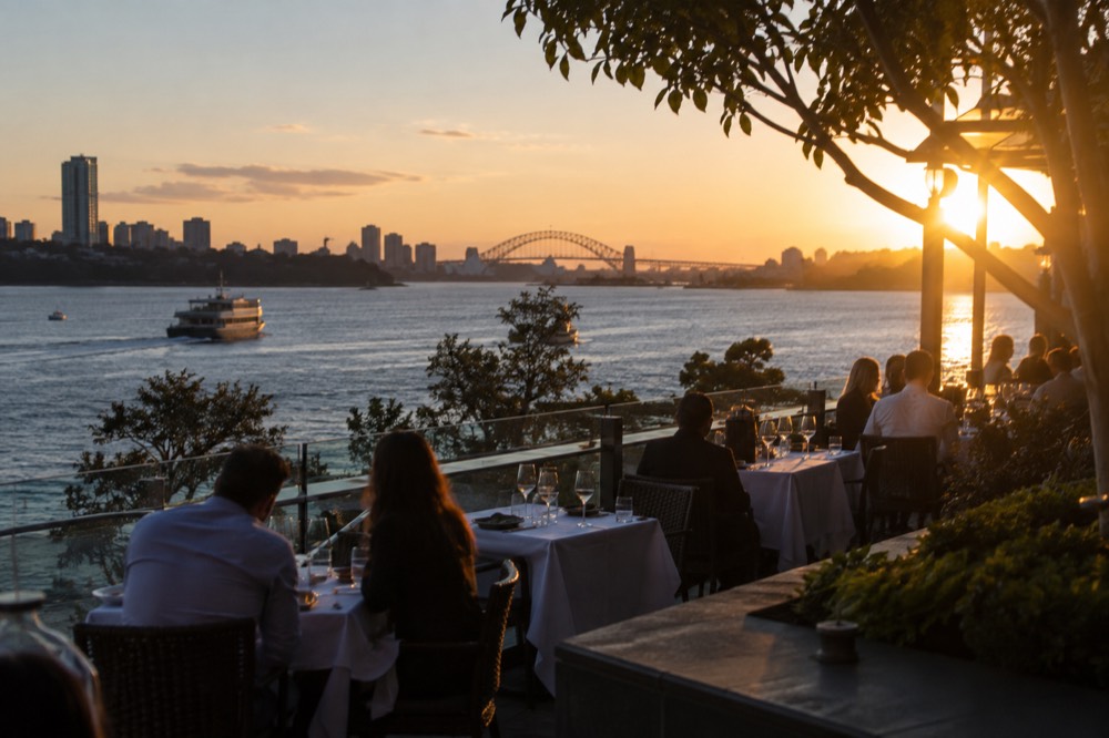 Outdoor harbourside dining tables with white tablecloths and water views at dusk
