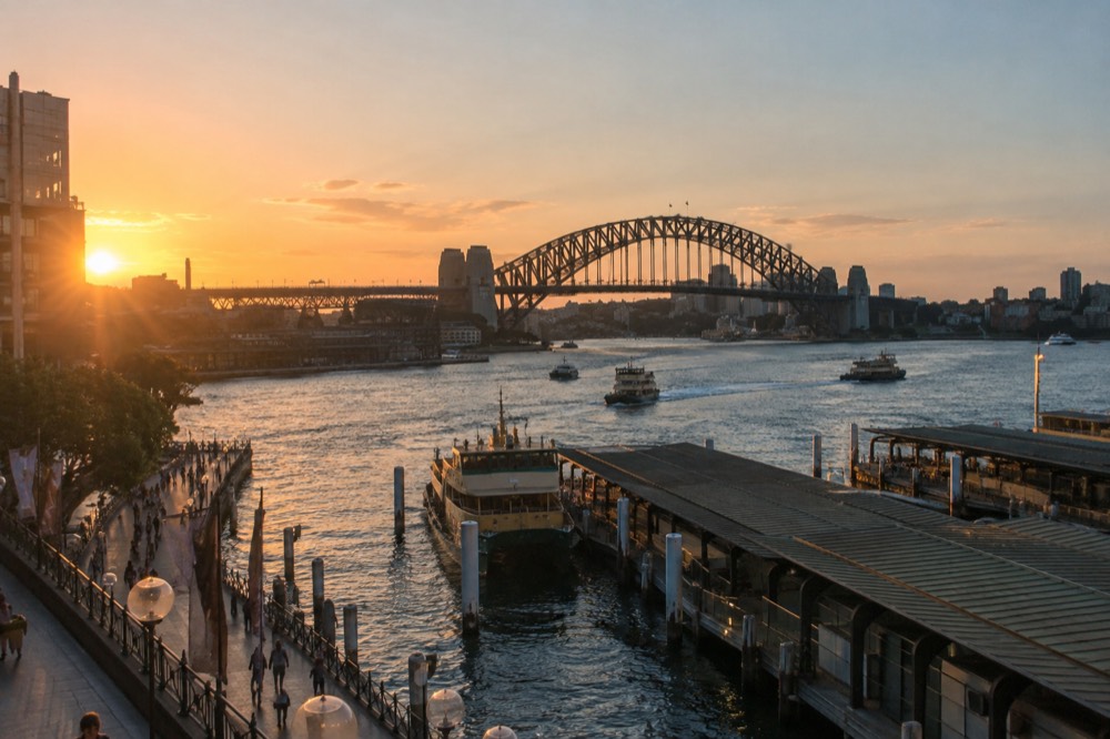 The Sydney Harbour Bridge seen across the water from the Circular Quay promenade at sunset