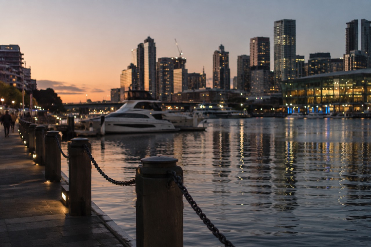 Darling Harbour waterfront promenade with moored boats and city buildings on a clear day