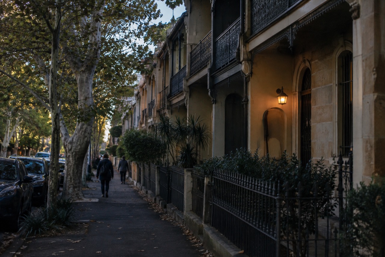 Sandstone terrace houses along a tree-lined Darlinghurst street at midday