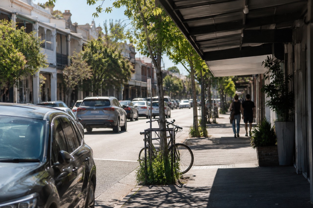 A wide shopfront street with awnings and street trees in a Sydney inner west suburb
