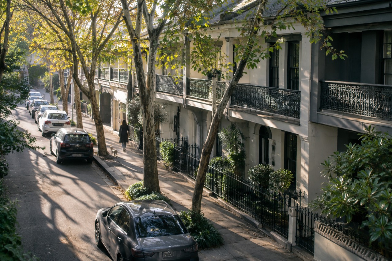 Terrace houses with wrought-iron balconies along a tree-lined Surry Hills street