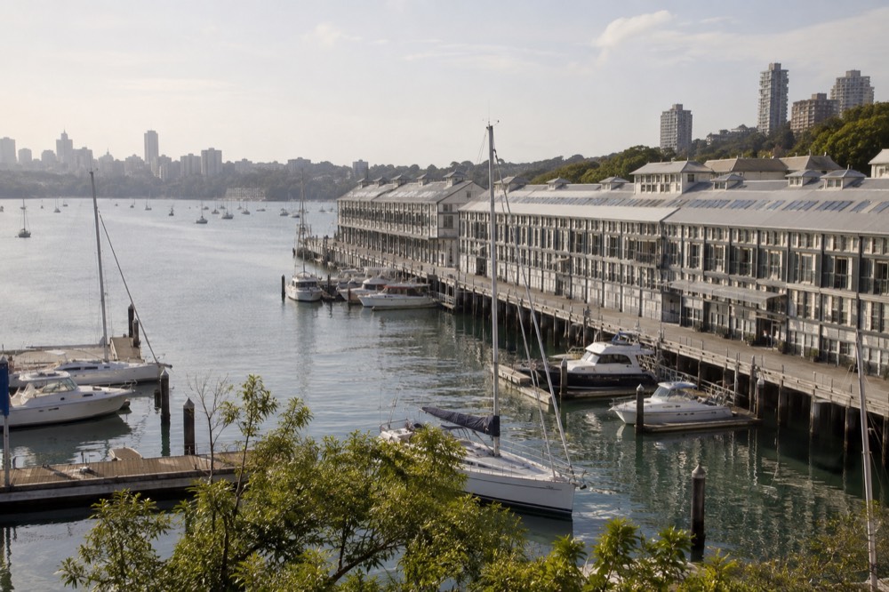 Historic timber finger wharf buildings along the water at Woolloomooloo Bay with moored boats