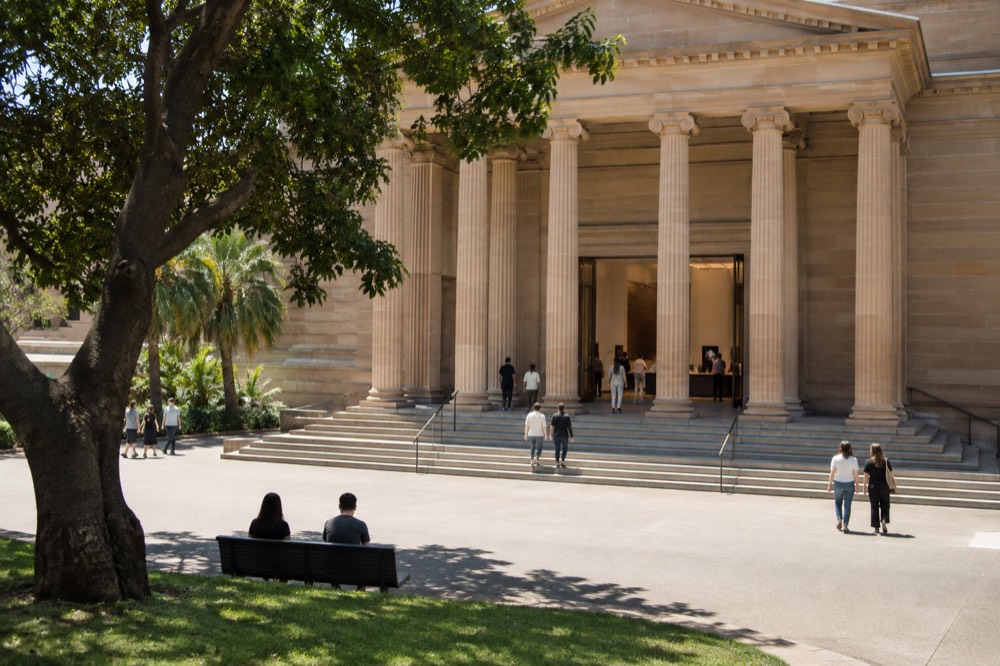 Gallery entrance hall with visitors at an information desk under warm lighting