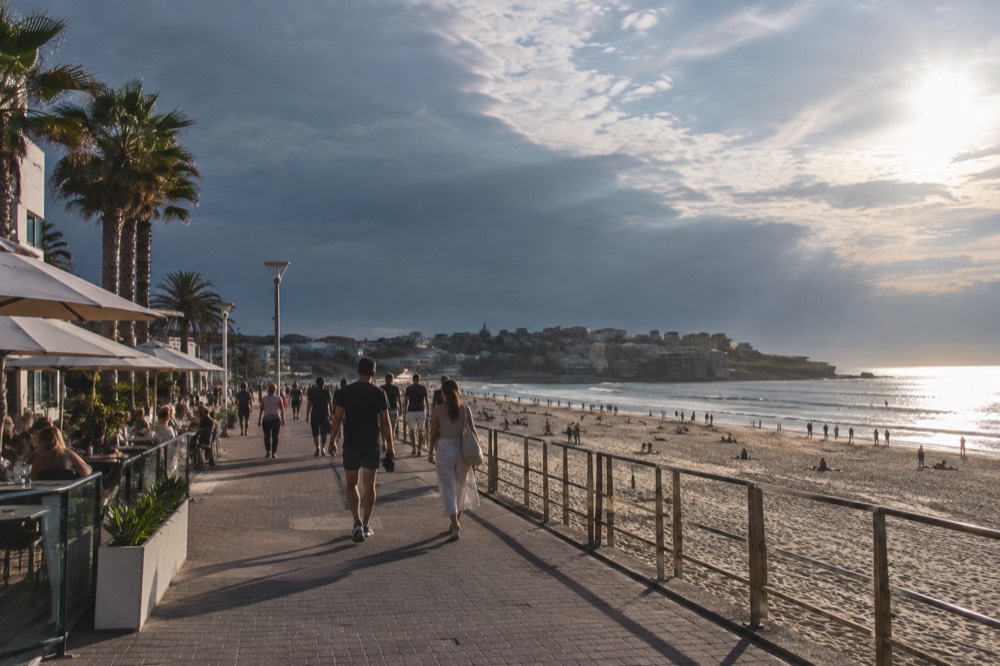 Beachfront promenade with cafes and palm trees along a wide sandy beach