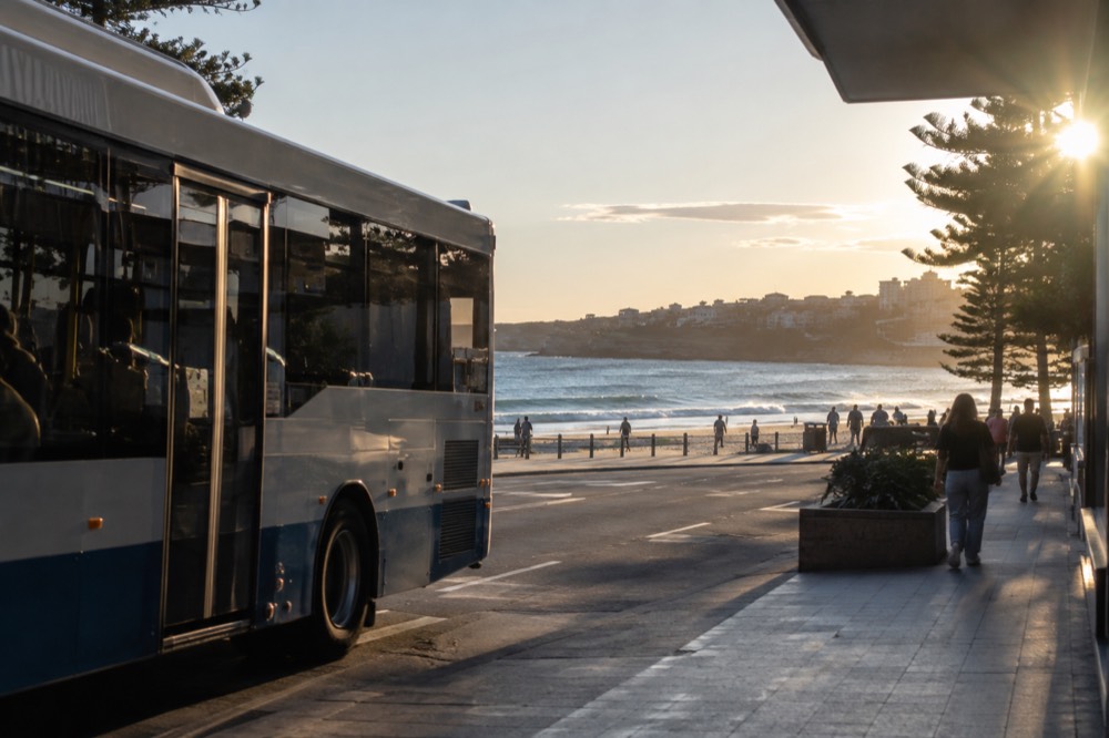 Bus waiting at a suburban street stop near a beachfront shopping strip