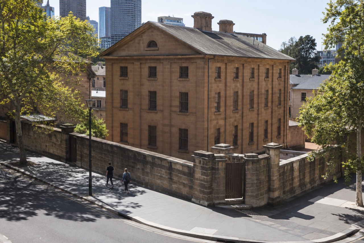 A sandstone Georgian building with small barred windows on a sunny city street corner