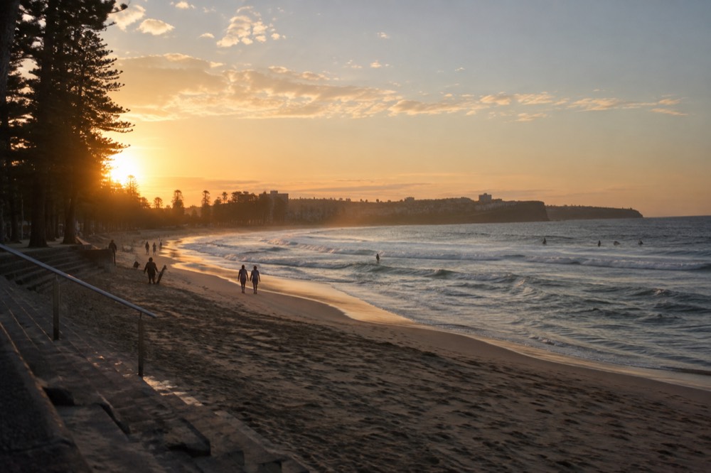 Wide view across a surf beach toward a headland at dusk