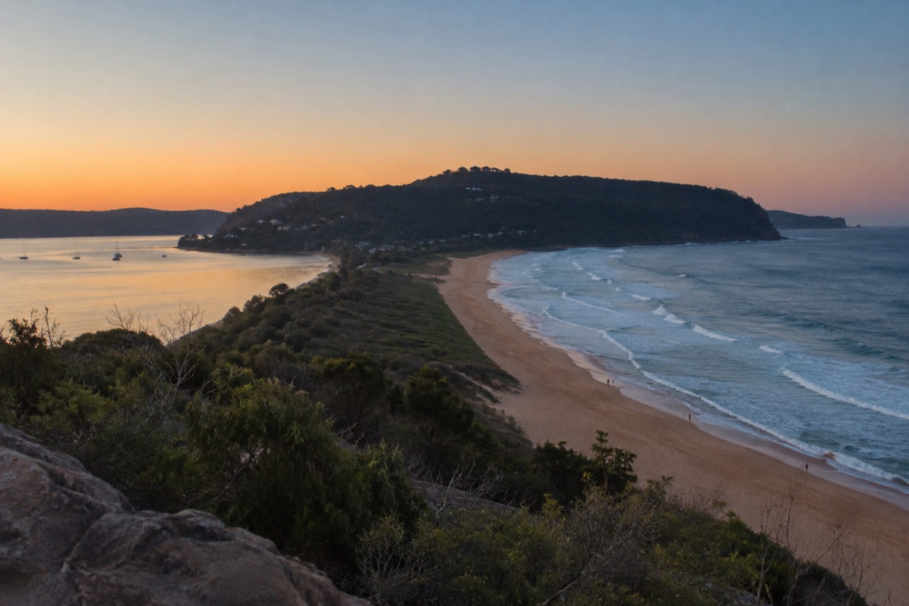 Long sandy spit between the ocean and calm Pittwater under a clear sky