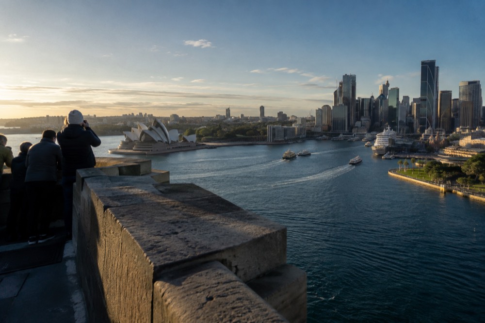The Sydney city skyline and harbour seen from an elevated deck in late afternoon light