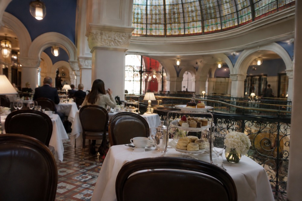 Formal tearoom under a stained glass dome with white tablecloths and tiered cake stands