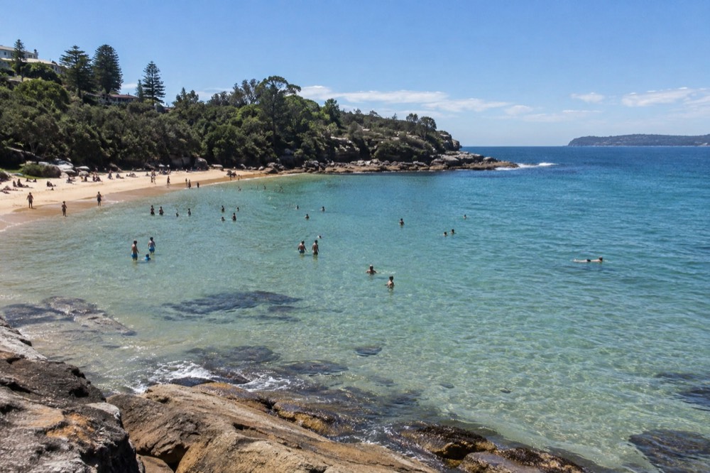 A wide sheltered cove with shallow calm water and a rocky point on the horizon
