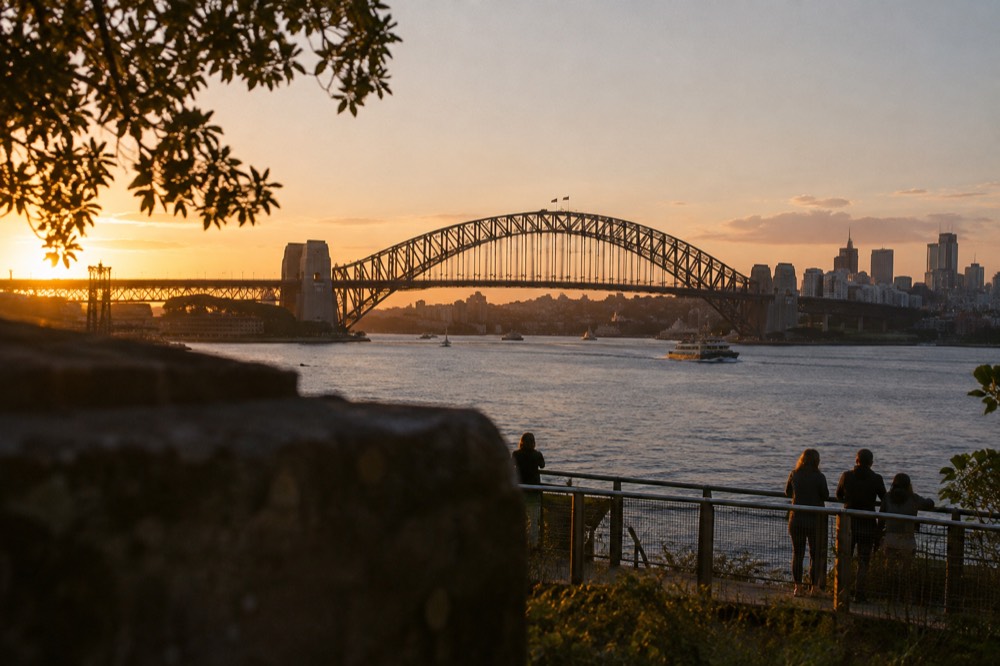 The Sydney Harbour Bridge spanning the water at dusk with the city skyline behind it