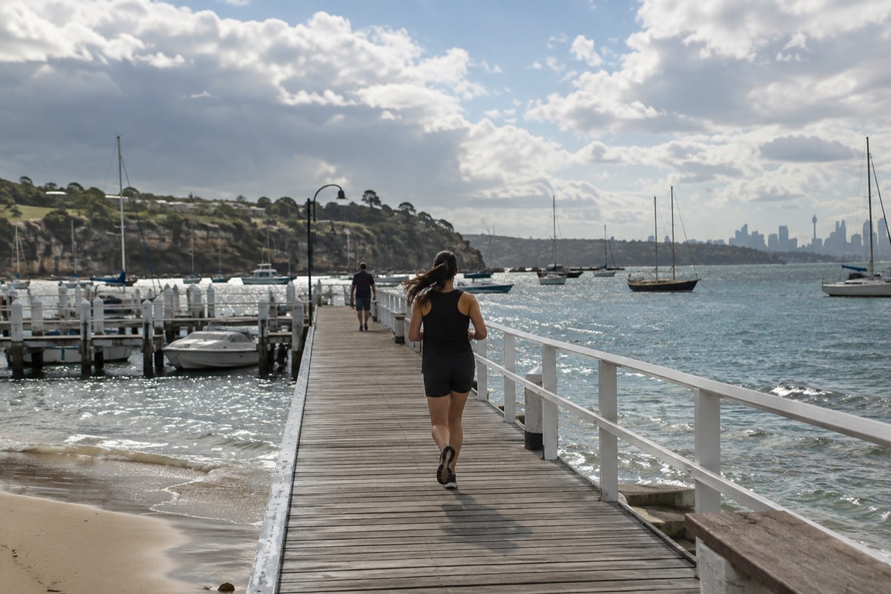 A quiet harbourside wharf with moored boats and sandstone headland in the background