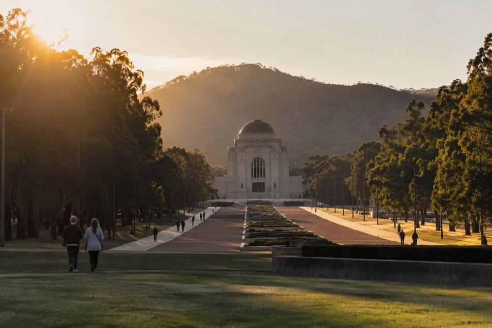 Sandstone memorial building at the head of a long ceremonial avenue under clear sky