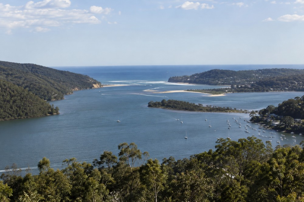 Aerial view of a coastal lake opening to the sea between green headlands