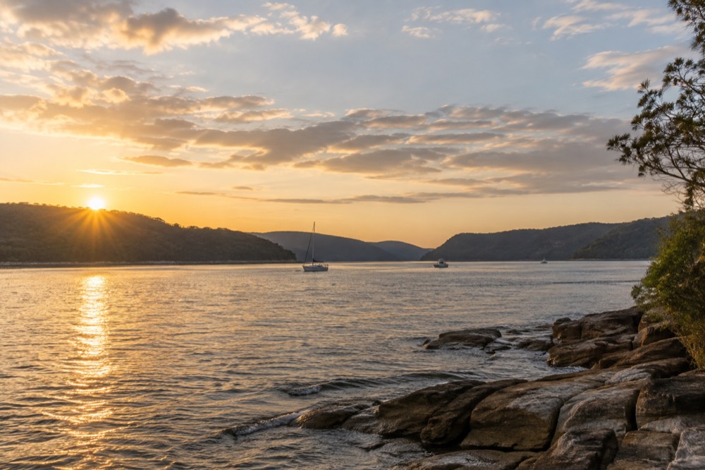 Golden late afternoon light across a wide river with distant blue ridgelines