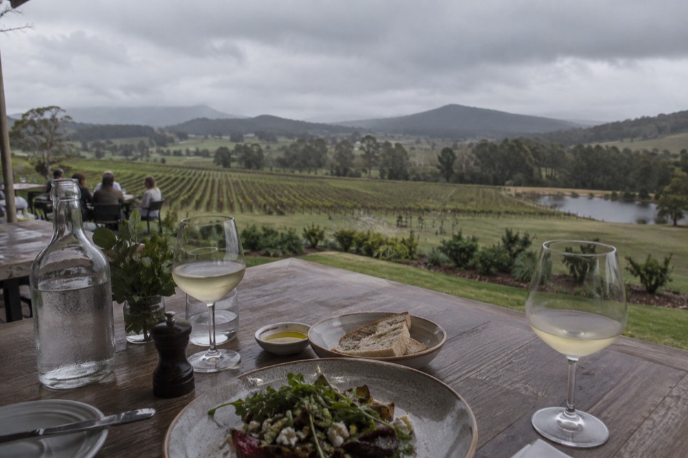An outdoor table set for lunch overlooking rolling vineyard hills
