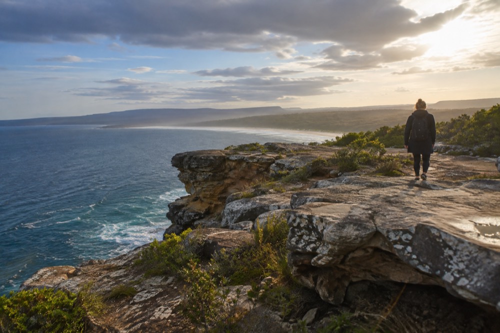 Sandstone cliffs above rolling green valleys with a distant blue mountain ridge
