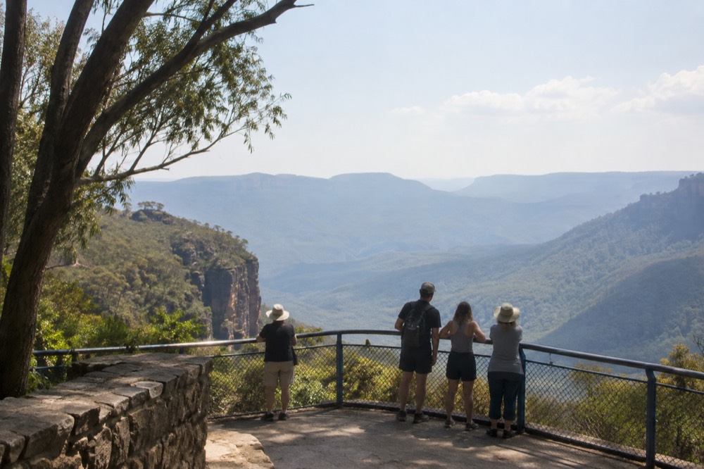 A stone lookout platform above a wide forested valley with hazy blue ridges