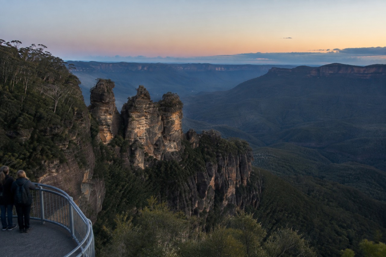 Sandstone formation of three peaks above a forested valley at golden hour