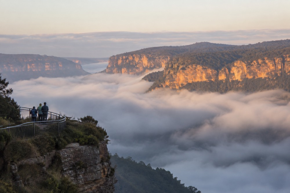 Low cloud filling a valley at sunrise with bright cliffs above the mist