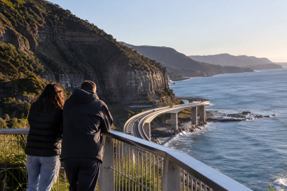 A coastal lookout above a curved ocean road with clear winter sky