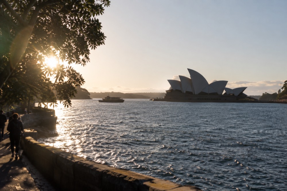 Sydney Opera House sails seen across sparkling harbour water on a clear morning