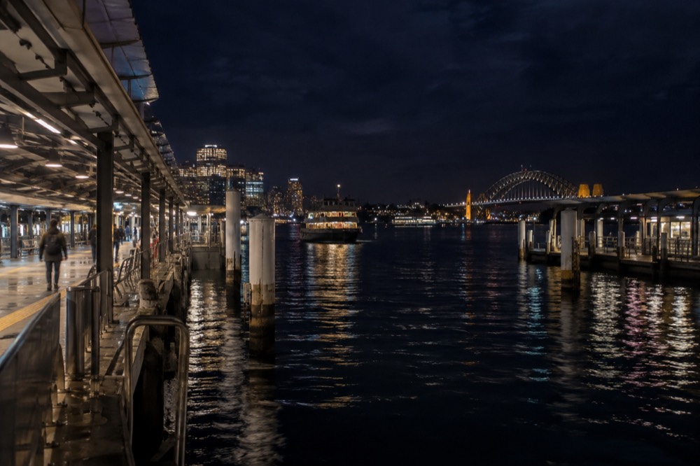 A Sydney train platform at night with the platform lights reflecting on the tracks