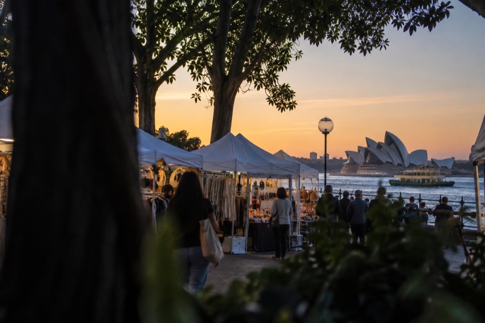 Outdoor weekend market stalls with white canopies in a tree-lined Sydney square