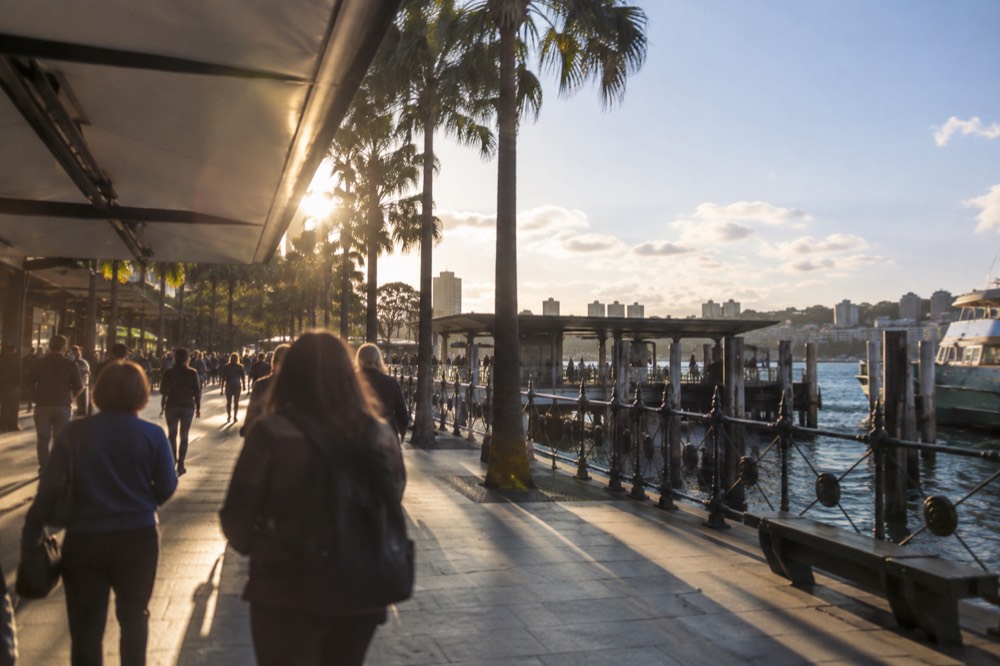 Busy pedestrian shopping street in Sydney with awnings, banners and storefronts at dusk