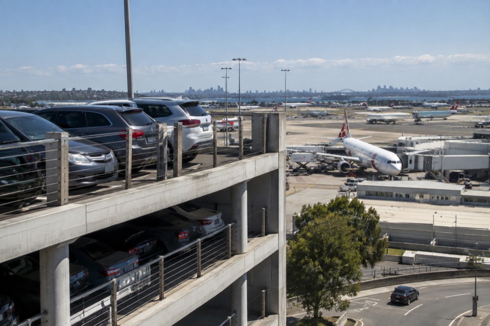 Multi-storey car park exterior at Sydney Airport with planes on the tarmac behind
