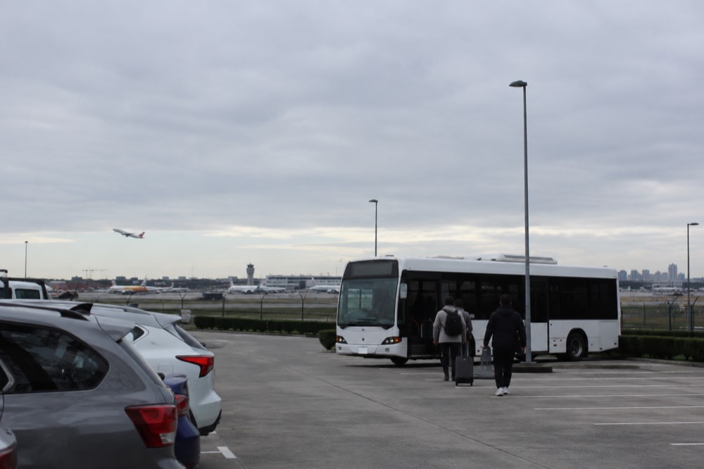 Open-air parking lot with a shuttle bus waiting near a row of cars