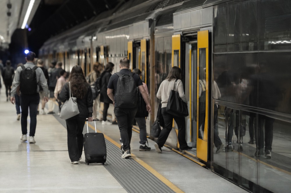 A suburban train waiting at an underground airport platform with passengers boarding