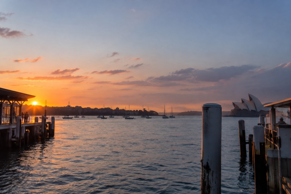 Harbour cove at sunrise with calm water and soft pink sky over anchored boats